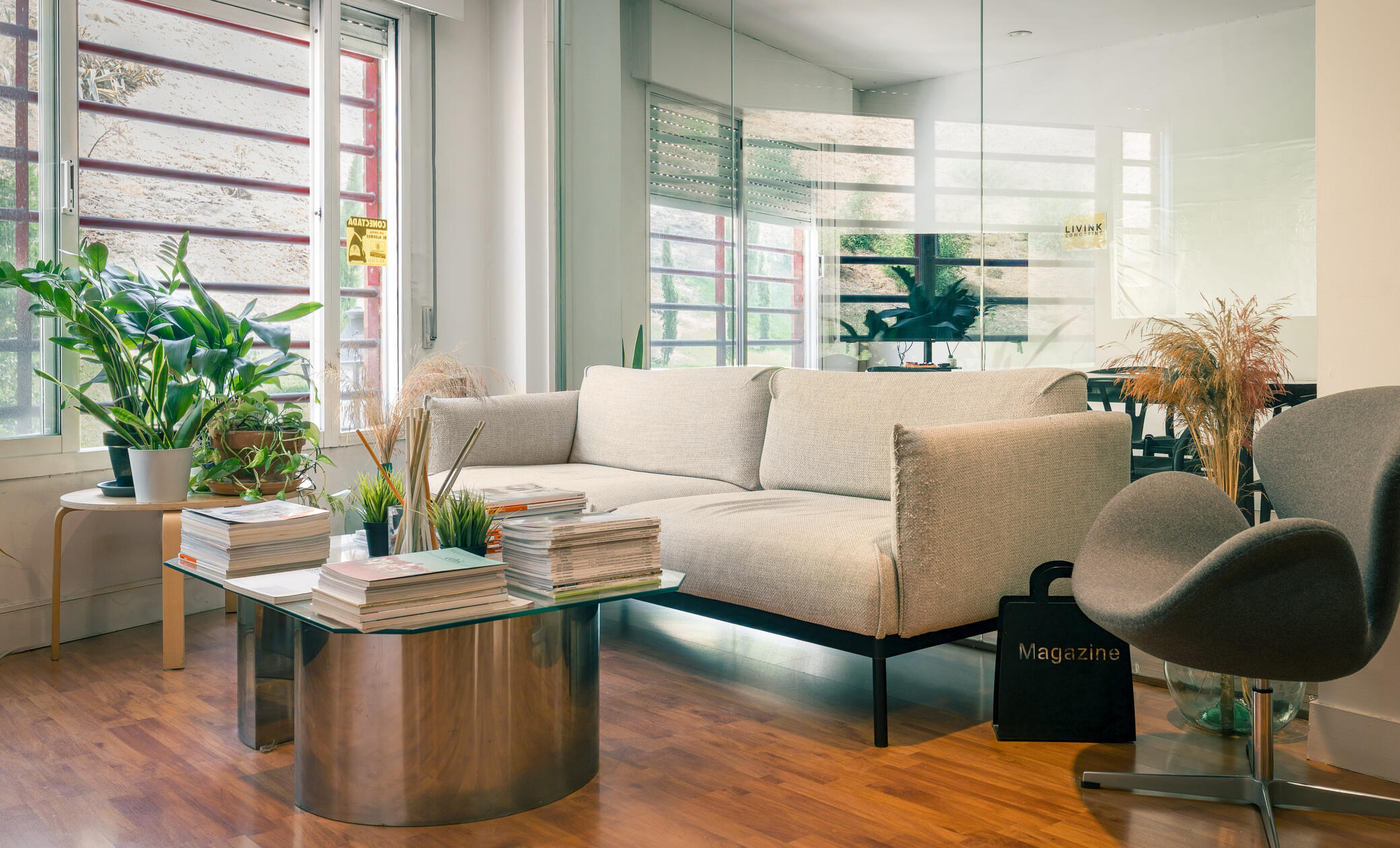 LIVINK Coworking | Zona de entrada y recepción a la oficina 2. Sofá, revistas, plantas.